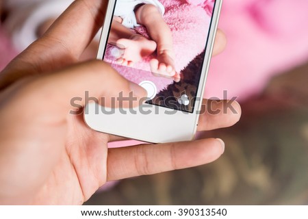 Mother using smartphone take a photo of her baby. Baby picture is a most popular in social networks
