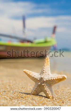Starfish on caribbean sandy beach with long tail boat on background