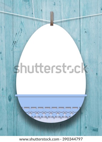 Close-up of hanged blank decorated Easter egg with peg against aqua wooden boards background