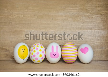 Easter eggs on wooden background. Painting with cute cartoon , heart , bunny and chicken.