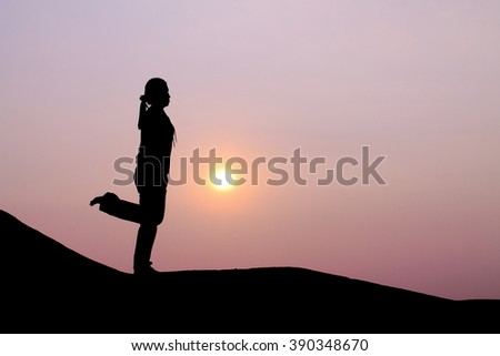 Silhouette picture of a woman plays yoga on the hill in sunrise scene