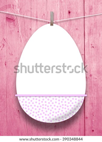 Close-up of one hanged blank decorated Easter egg with peg against pink weathered wooden boards background