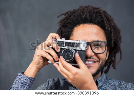 Happy hipster man smiling with toy camera on rustic backgorund