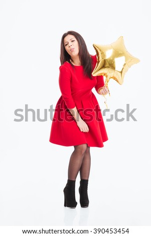 Full length portrait of a young woman in red dress holding balloon and showing tonque isolated on a white background