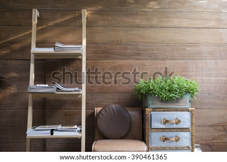 Book shelf ladder, leather chair, and vintage drawer with plant wooden vase on it with wooden wall background