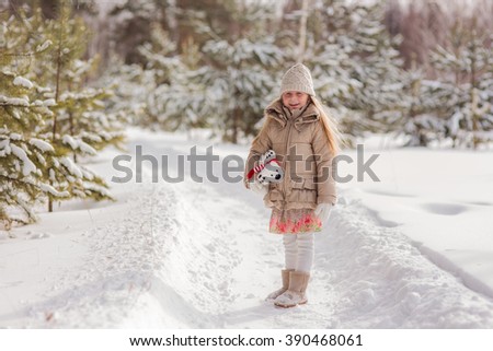 girl walks on the snowy woods with his favorite toy polar bear
