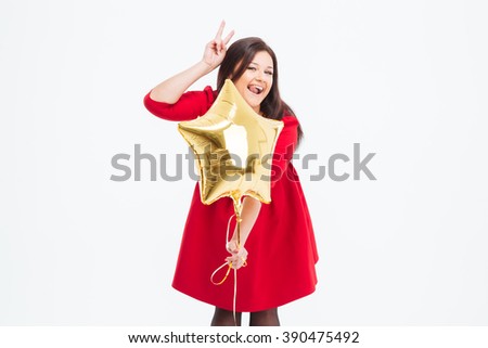 Funny woman in red dress holding balloon and showing tongue with sign of horns isolated on a white background