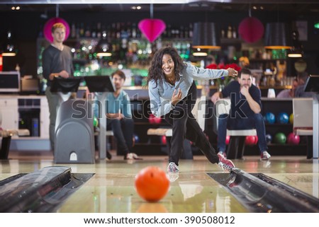 smiling woman throwed the ball at the bowling lane with her supporting friends