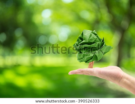 male hand holding paper shape tree on blurred green bokeh background of tree nature : world environment day Royalty-Free Stock Photo #390526333