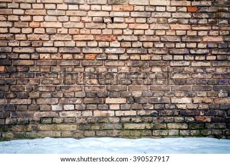 Yellow brick wall and a ground covered with snow     