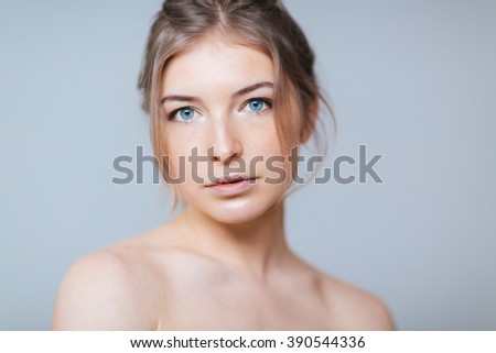 Beauty portrait of a young attractive woman looking at camera over gray background
