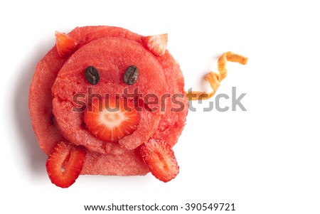Food art creative concepts. Funny and cute pig made of watermelon, strawberry, carrots and coffee beans on a blue plate isolated on a white background.
