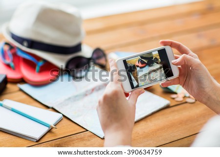 vacation, tourism, travel, technology and people concept - close up of woman with smartphone photographing map and travel stuff