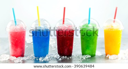 Panoramic Still Life of Colorful Frozen Fruit Slush Granita Drinks in Plastic Take-Away Cups with Lids and Drinking Straws on Cold Metal Surface with Ice Royalty-Free Stock Photo #390639484