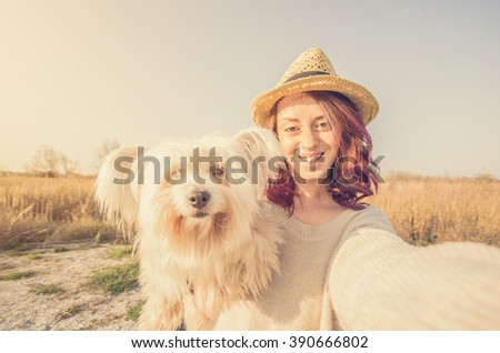 Attractive caucasian girl is taking a selfie with her dog in the countryside - caucasian people - people, animal, lifestyle, nature and technology concept