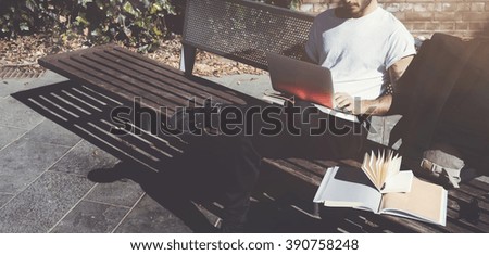Photo man sitting city park bench and texting message notebook. Using wireless internet. Studying at the University,  preparation for exams. Use book, generic design laptop. Wide, soft shadows