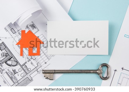 Real estate concept. Silver key with house figure and blank business card on blue background. Top view.