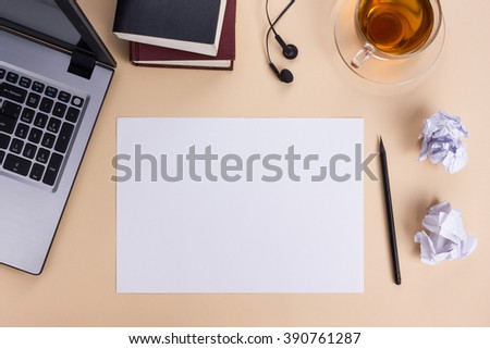 Office table desk with set of colorful supplies, white blank note pad, cup, pen, pc, crumpled paper, flower on beige background. Top view and copy space for text