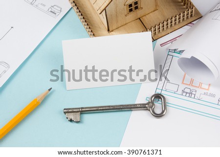 Real estate concept. Silver key with house figure and blank business card on blue background. Top view.
