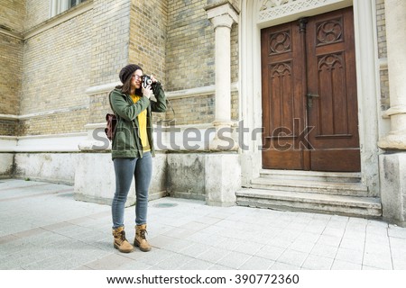 Modern young woman taking a pictures on a vacation. She is taking a pictures of the architecture.