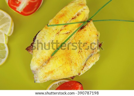 roast sea sole fish fillet served on bread with tomatoes,olives and chives on green plate isolated over white background