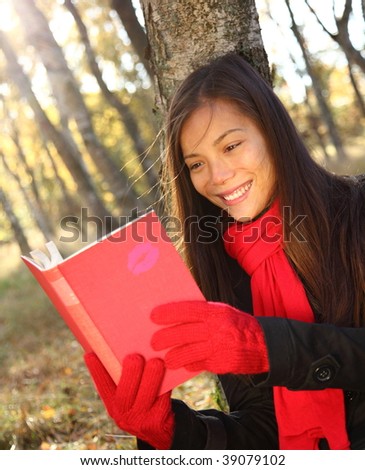 Reading outdoors. Beautiful young woman reading a book outside in autumn.