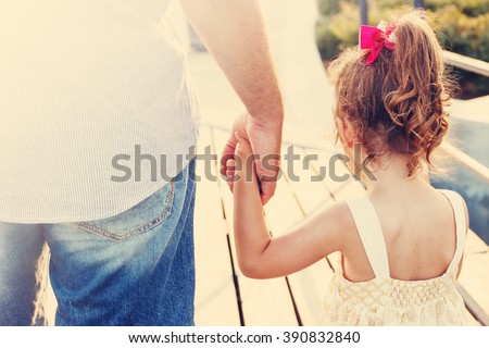Toned portrait of Father and daughter holding hand in hand at sunset Royalty-Free Stock Photo #390832840