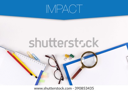 High angle view of various office supplies on desk with a word IMPACT