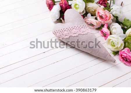 Decorative heart and pink and white flowers on white wooden background. Selective focus. Place for text. 
