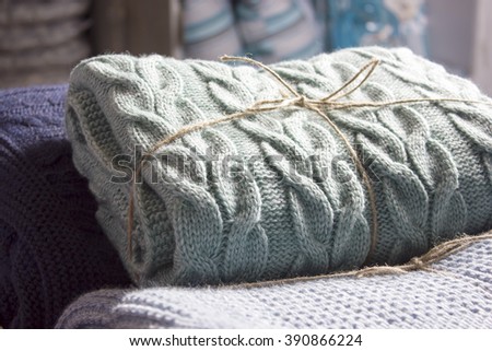 Warm knitted blankets folded stack. Plaid mint color over blue homemade quilts, hand-knitted. The cosiness and comfort in the cold winter
