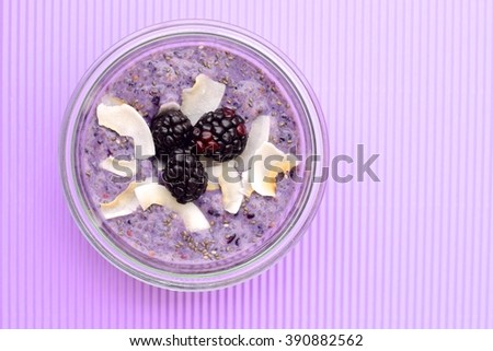 A healthy breakfast blackberry coconut chia seed pudding on purple background. Concept of healthy food. Top view. Selective focus

