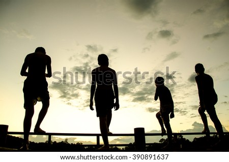 Young boys jumping into a lake from a dock at sunset