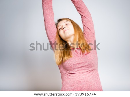 Portrait of a young woman doing exercises after waking up, isolated on a gray background