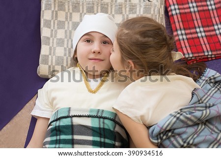 little girl kissing her sister lying on the plaids in the gym