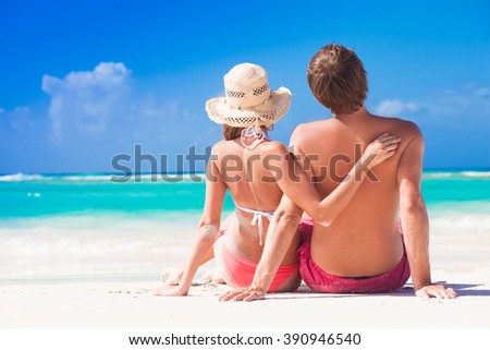 back view of beautiful couple relaxing at caribbean beach. remote tropical beaches and countries. travel concept