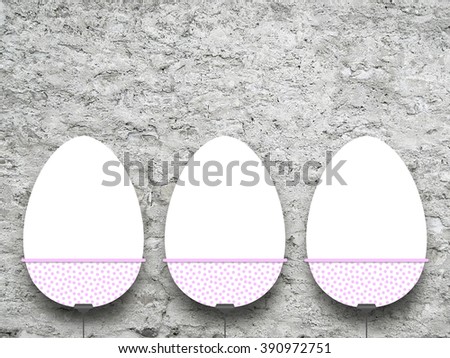 Close-up of three hanged Easter egg blank frames against grey rough concrete wall