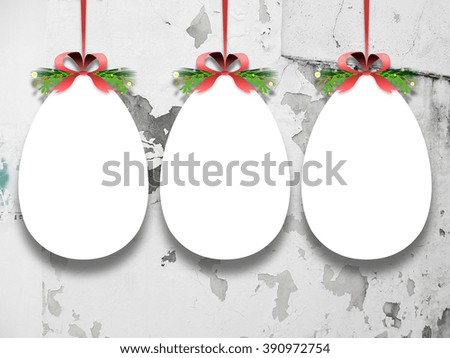 Close-up of three hanged Easter egg blank frames with ribbons against weathered concrete wall