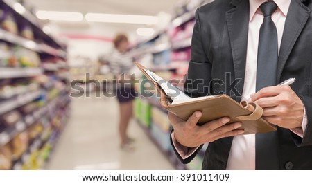 Businessman writing the note book on Abstract blurred photo of store in department store bokeh background