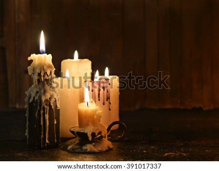 Group of evil candles burning in the darkness and copy space on wooden background. Black magic ritual or scary halloween rite. 