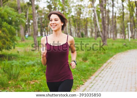 Young beautiful female athlete with cardio sensor and heart rate monitor on hand running in park smiling happy. Concept of wearable devices and modern gadgets