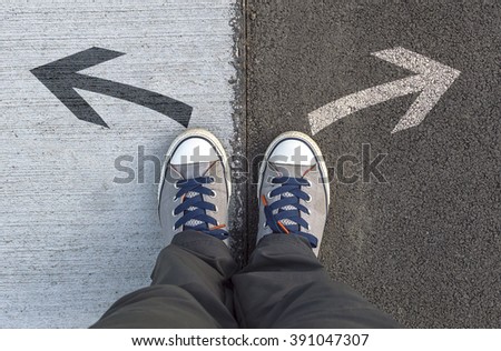 Sneakers standing on a road with arrows. Selective focus.