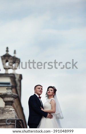Happy elegant newlywed couple hugging on old white balcony