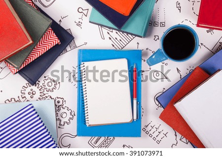 Office table desk with blue supplies, white blank note pad, cup, pen, pc, crumpled paper, flower on wooden background. Top view