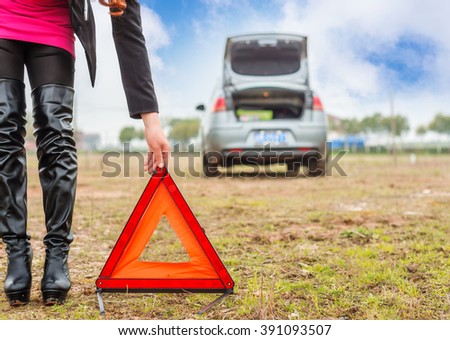 Woman putting a triangle on a road,car trouble