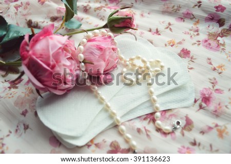 Woman hygiene protection, close-up.menstruation calendar with cotton tampons,pink rose, a symbol of femininity.female pearl necklace.feminine pads