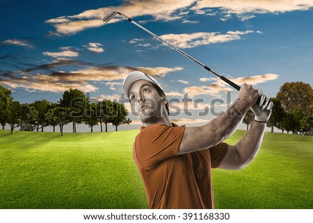 Golf Player in a orange shirt taking a swing, on a golf course.