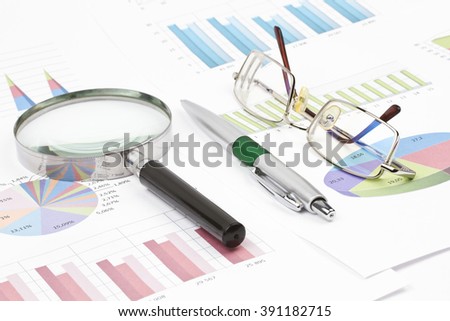 Business still-life of graph, eyeglasses, magnifier, shiny pen