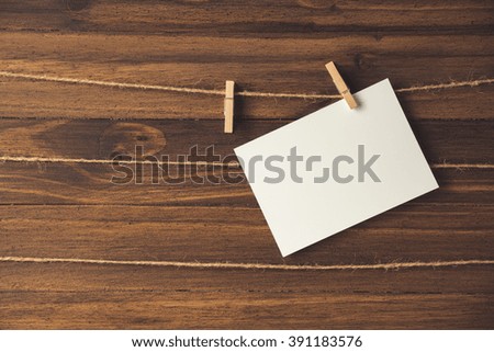 single empty photo frames hanging with clothespins on wooden background