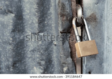 Close up of Padlock with old corrugated iron fence background.