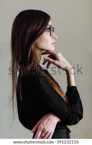 Profile of  Attractive young business woman in glasses  in side view standing  solving a problem staring thoughtfully up into the air with her finger to her chin. Empty  copy space. Royalty-Free Stock Photo #391232116